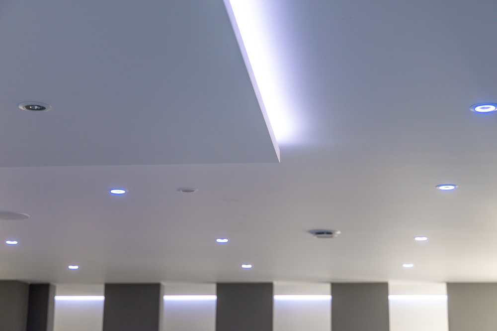 Modern ceiling with IC-Rated Downlights, recessed LED lights, indirect strip lighting, and smooth white surface.